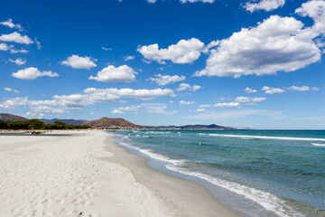 Obraz premium Beach at Sardinia, Italy. Sandy Mediterranean sea beach between Santa Lucia and La Caletta with white clouds on blue sky.