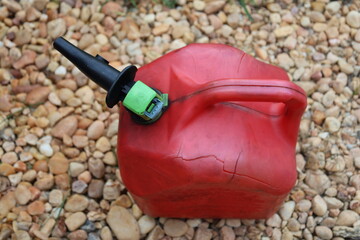 Damaged Plastic red gas can on asphalt canister