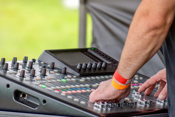 Hand of a DJ on an outdoor mixer console in the summer