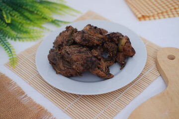 black pepper chicken meat in white plate on bamboo mat.