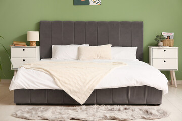 Interior of stylish modern bedroom with fresh clean bedding, bedside tables and home decor