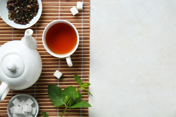 Beautiful composition with tea pot, cup of tea and green leaves on light background