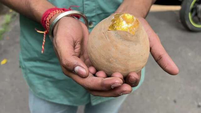 A shot captures a man holding a flowerpot firecracker or Anaar, ready for the festive celebration during Diwali in India.