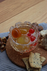 Italian Mostarda di Cremona with candied fruits in a glass bowl with snacks on wooden table. Traditional Italian mustard 