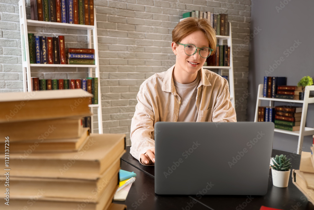 Wall mural Male student studying with laptop at table in library