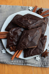 Italian traditional festive cookies called Mostaccioli or Mustaccioli on a plate on gray tablecloth on wooden table. Christmas cookies made mith Pisto, a mix of various spices