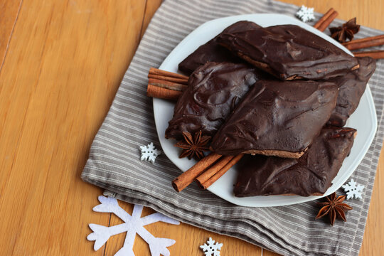 Italian traditional festive cookies called Mostaccioli or Mustaccioli on a plate on gray tablecloth on wooden table. Christmas cookies made mith Pisto, a mix of various spices