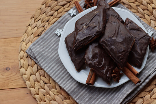 Italian traditional festive cookies called Mostaccioli or Mustaccioli on a plate on gray tablecloth on wooden table. Christmas cookies made mith Pisto, a mix of various spices