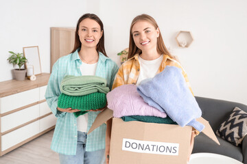 Young women with clothes for poor people at home