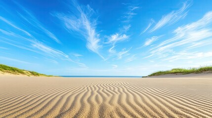 Fototapeta premium Endless golden sand dunes under a bright blue sky with rippling patterns from the wind