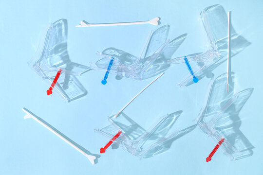 Gynecological speculums with pap smear test tools on light blue background