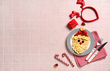 Plate with pancake in shape of Santa Claus on pink tile background