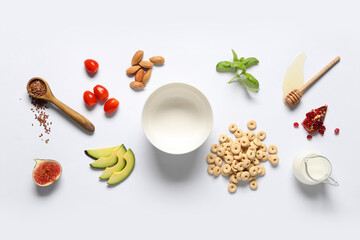 Empty bowl with cereal breakfast, milk and ingredients on white background