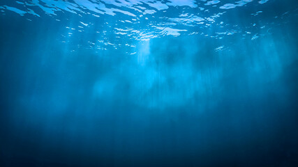 Underwater photo of rays of sunlight coming through the surface of the blue ocean. From a scuba dive - Unspecified.