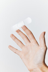 Adhesive bandage held by a hand against a white background, with space for text or image