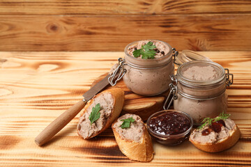 Jars of tasty pate with toasts, sauce and parsley on wooden background