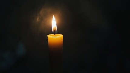 A single candle flame glows in the dark.