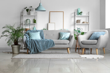 Comfortable sofa, armchair and houseplant in interior of living room