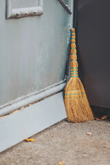old broom at a door. A broom for cleaning the territory is leaning against the wall in the street