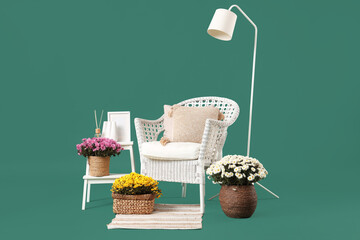 White armchair, floor lamp and chrysanthemum flowers on green background