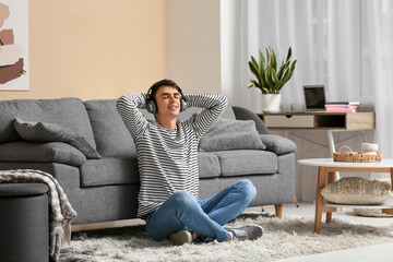 Handsome young man in headphones listening to music at home