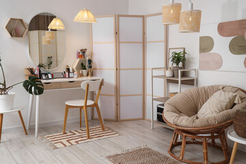 Interior of light dressing room with makeup table, folding screen and armchair