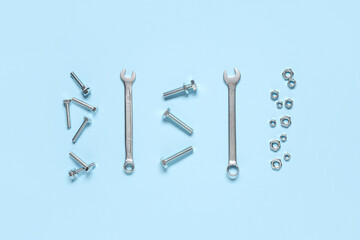 Naklejka premium Tap bolts, chrome nuts and wrenches on blue background