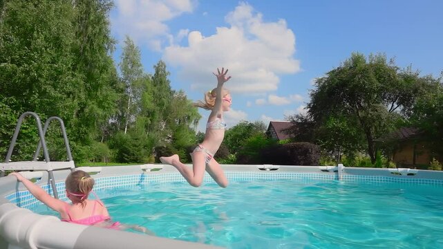 Girl in a pink pompom bikini is jumping with splashes of water into the pool on the backyard. High quality 4k footage