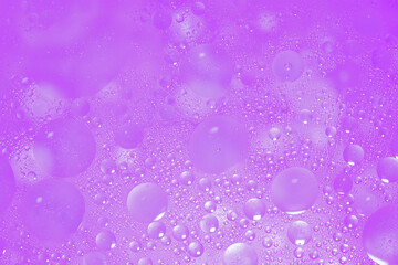 Vibrant bubbles of oil float on water, crafting abstract patterns full of colors and textures.