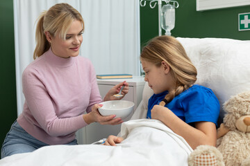 Tender Care A Loving Mother Tenderly Feeding Her Sick Daughter in a Hospital Room