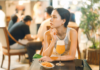 Single young adult asian woman drinking beer at bar and restaurant
