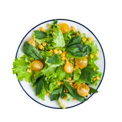 Fresh mixed green salad with yellow cherry tomatoes and corn served in a round plate