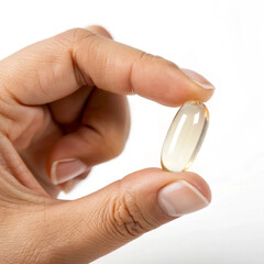 Hand Holding a Small Orange Capsule on White Background