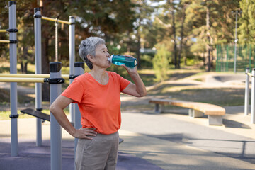 elderly asian woman drinking water while doing sports, concept of health and active lifestyle of elderly people