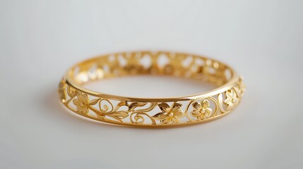 A gold bracelet with a delicate floral pattern, placed on a white background.