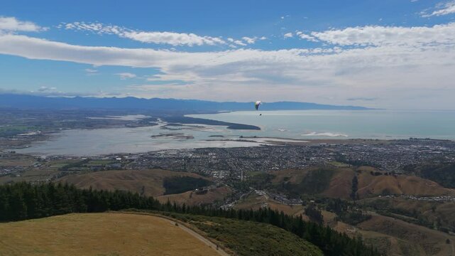 Paraglider taking off and gliding above Nelson region, New Zealand