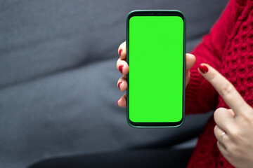 Close up of a woman holding a smartphone wit a green screen
