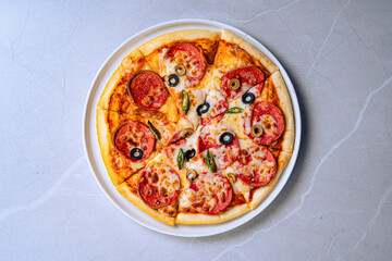 Delicious Pepperoni Pizza With Olives And Cheese On White Plate, Top view of a delicious pepperoni pizza topped with olives, cheese, and peppers on a white plate. Perfect for food lovers.