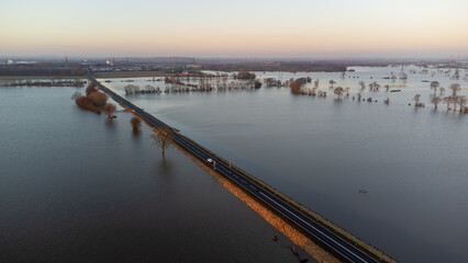 Obraz premium Aerial view of vehicles on A19 main road on raised embankment above flooded landscape 