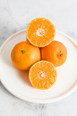 Whole and sliced tangerines on a white plate