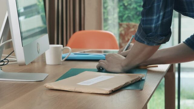 A desk with a computer monitor, a red chair, a green mat, a cup, a tablet, and a stack of papers