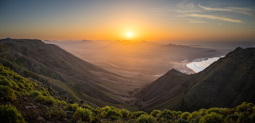Obraz premium Distant view on Playa de Famara and Timanfaya Nationalpark at sunset from Famara cliffs, Teguise, Lanzarote, Spain