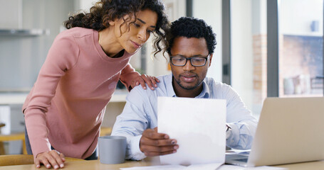 Interracial couple, paperwork and laptop with finance for budget planning, expenses or bills at...