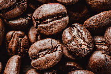 Close-up of roasted coffee beans, showcasing rich brown tones and textured surfaces. Perfect for coffee-related designs, ads, or backgrounds. Highlighting the essence of a fresh brew.