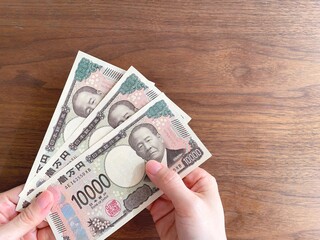 机上で3万円を持つ女性の手元