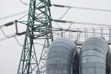 power transmission tower and pipeline against gray sky close-up