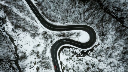 Arial view Winter road in forest with two cars taken from drone. Road in middle of a winter forest