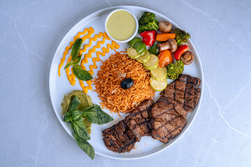 Grilled Steak With Mixed Vegetables and Rice on White Plate, A delicious meal of grilled steak served with mixed vegetables, seasoned rice, and sauce on a white plate.