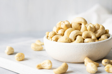 Raw cashew nuts in bowl or burlap sack on rustic table Healthy vegetarian snack, Anacardium occidentale