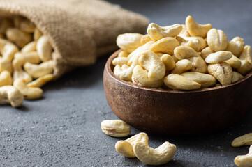 Raw cashew nuts in bowl or burlap sack on rustic table Healthy vegetarian snack, Anacardium occidentale